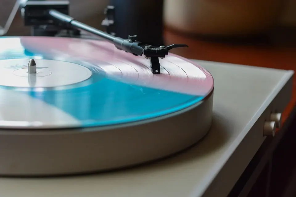 Main posant le bras d'une platine sur un disque vinyle noir en rotation