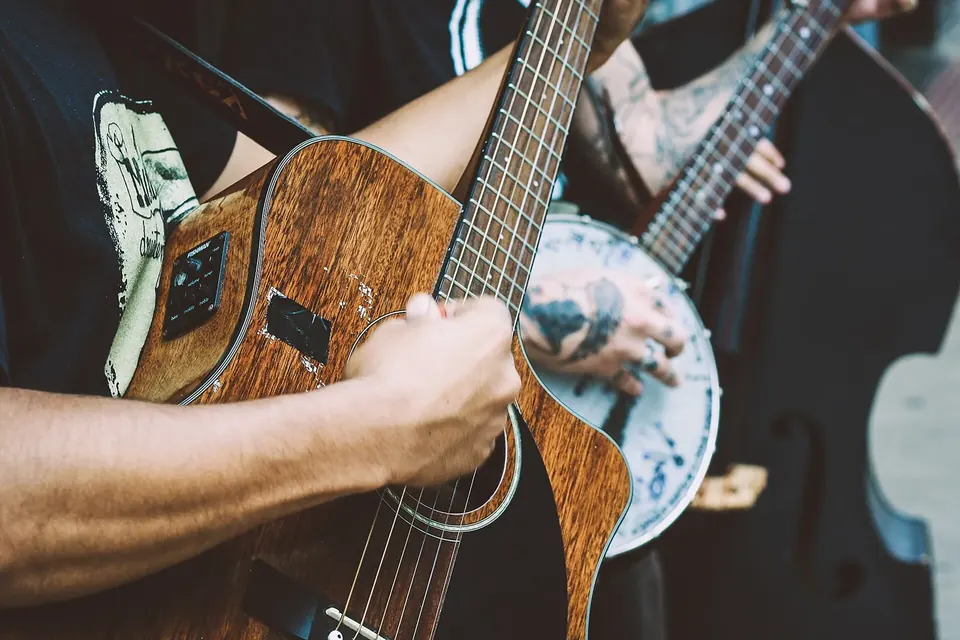 Mains sur le manche d'une guitare acoustique en train de jouer un accord