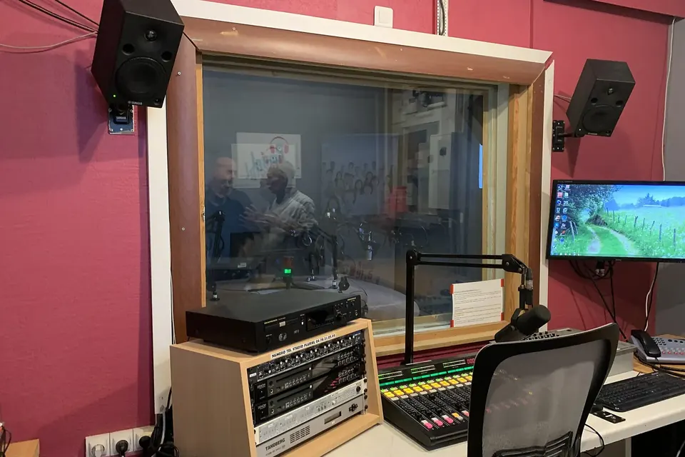 Studio d'une radio associative : table de mixage, micros sur bras articulés et écrans